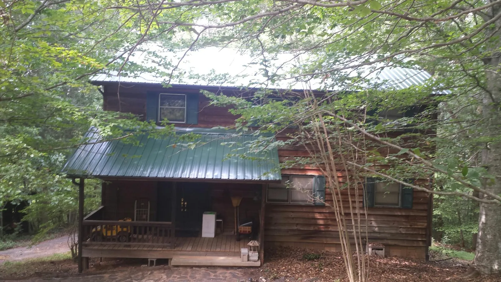 Green metal roof and covered porch on a log cabin in Hector