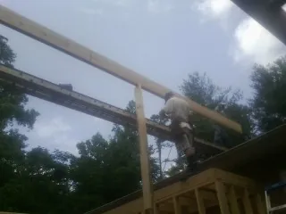 Carpenter setting a ridge beam over a new addition frame — Ice Dam Removal by Roofing Brothers in Hector