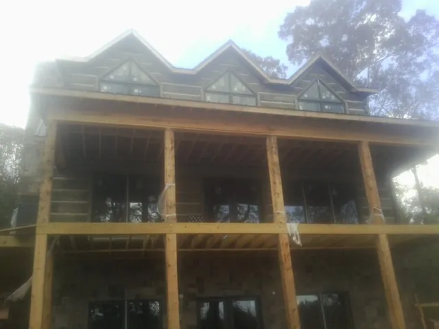 Dormers and porch framing on a large log home under construction — Roof Coating work by our crew in Hector