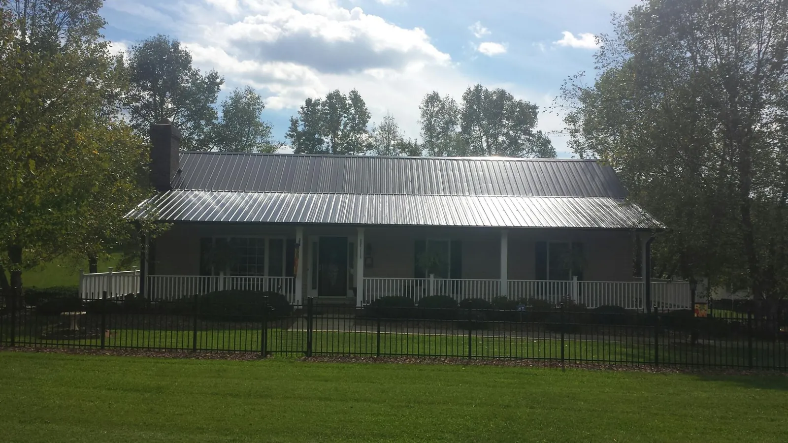 Gray metal roof on a brick ranch with a full width front porch — Gutter Guard Installation work by our crew in Hector