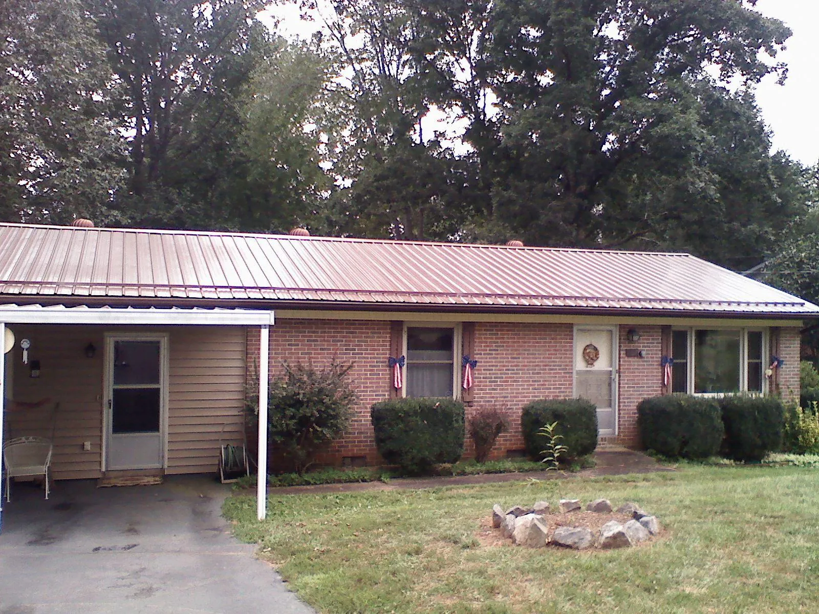 Bronze metal roof and carport on a brick ranch home — Roof Repair work by our crew in Hector
